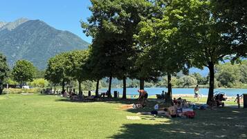 Un parco con prati, alberi e un lago sullo sfondo montuoso.