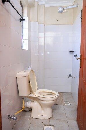 Une petite salle de bain compacte comprenant des toilettes, un espace douche et une porte.