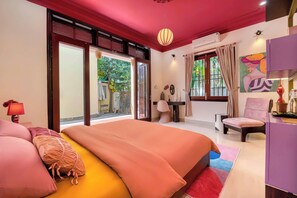 Un dormitorio con una cama grande, un escritorio, una silla y vistas al exterior.