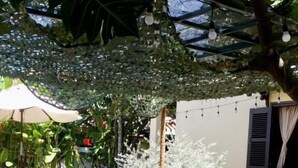 An outdoor dining area with a table and chairs, surrounded by greenery and a pool. - Xao xac Homestay (Da Nang)