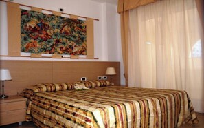 A hotel room with a large bed, two bedside lamps, a nightstand, and a tapestry on the wall. - Perfect holiday flat for six in beachfront complex (Bibione)