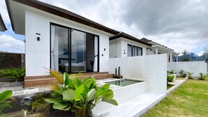 Una casa moderna con un amplio ventanal, piscina y jardín cuidado.