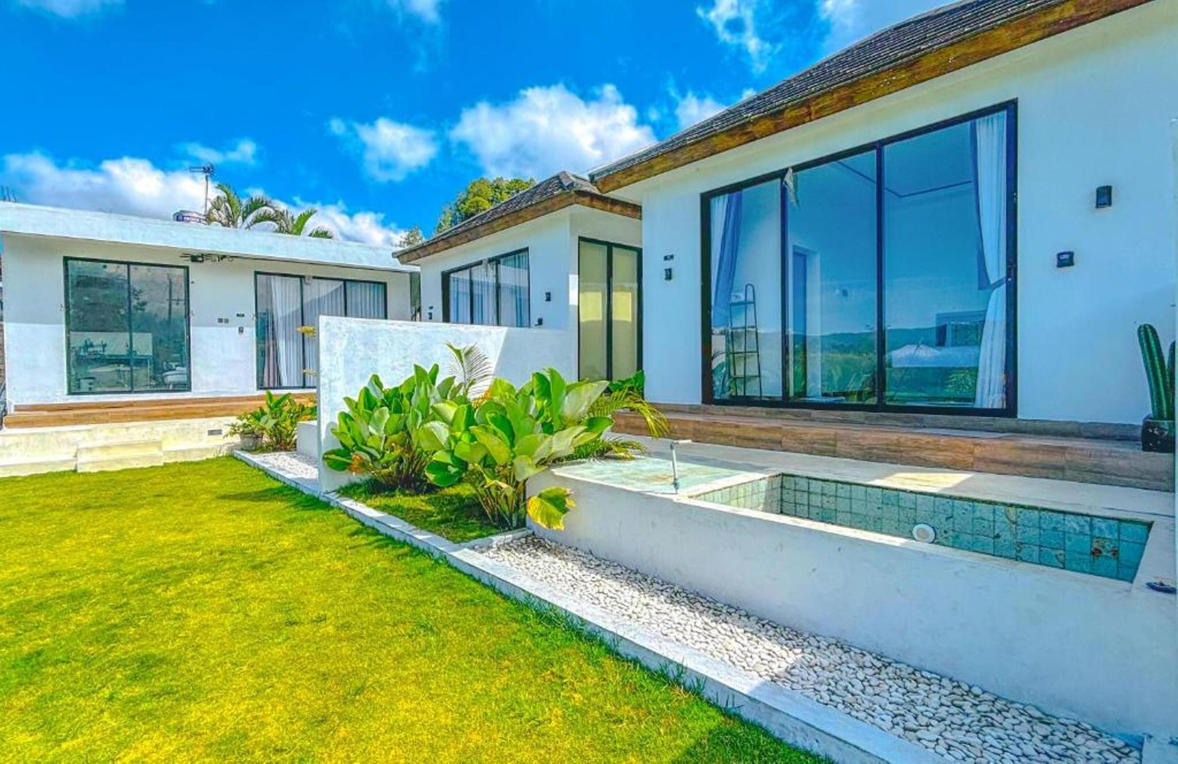 Una propiedad residencial moderna con un césped cuidado, piscina y ventanas amplias.