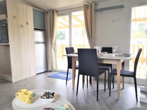 En matplats med ett bord för två personer, stolar, ett kylskåp och utsikt över omgivningen.