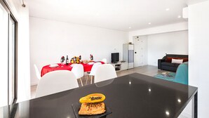 Een moderne woonruimte met een eethoek, een bank en een televisie.