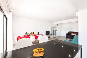 Ein zeitgemäßer Wohnraum mit Essbereich, einer Couch und einem Fernseher.