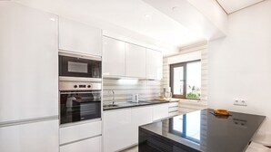Een moderne keuken met witte kastjes, roestvrijstalen apparatuur en een zwart aanrecht.