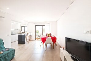 A modern living space with a dining area, kitchen, and a flat-screen TV. - Apartment with pool near beach in Albufeira (Albufeira)