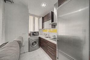 Une cuisine compacte équipée d’un lave-linge, d’un four à micro-ondes et d’un réfrigérateur.