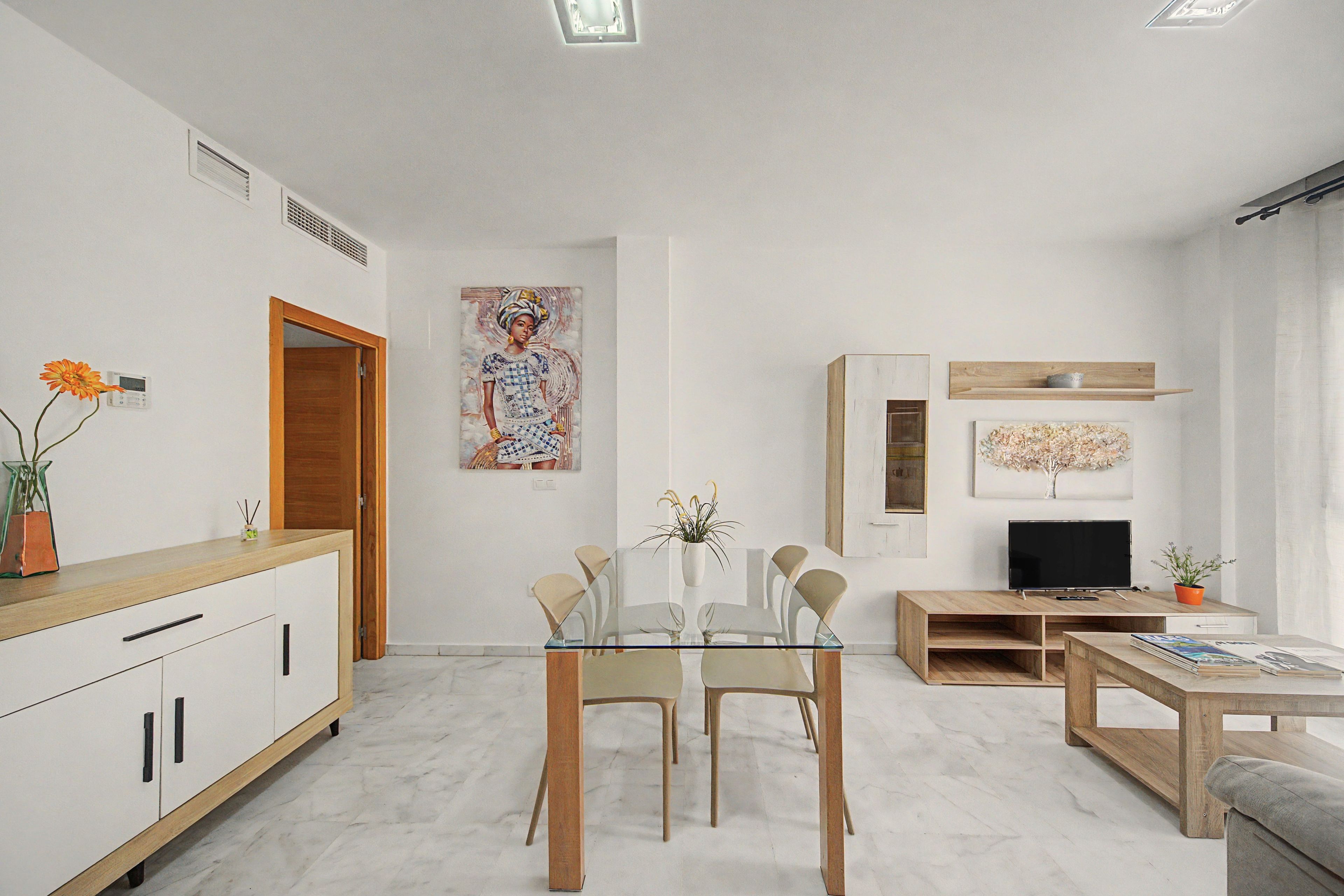 Un salon moderne comprenant un coin repas, un téléviseur et des œuvres d’art accrochées aux murs.