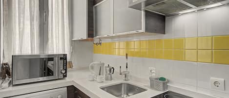 Cocina compacta equipada con microondas, cafetera, lavabo y lavadora.
