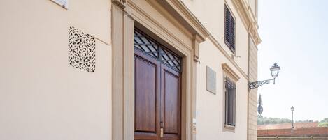 A building entrance with a double wooden door, a decorative metal grille, and a street lamp.