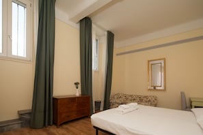 Une chambre à coucher avec un lit, une commode, un miroir et une fenêtre avec des rideaux.