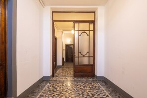 Un couloir doté d’un sol carrelé et d’une porte en bois avec des panneaux de verre.