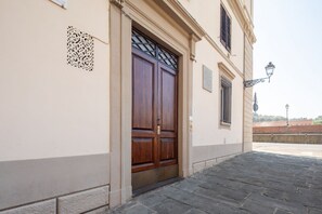 A building entrance with a double wooden door, a decorative metal grille, and a street lamp. - Cavalleggeri Palace - 3-Bedroom Apartment (Firenze)