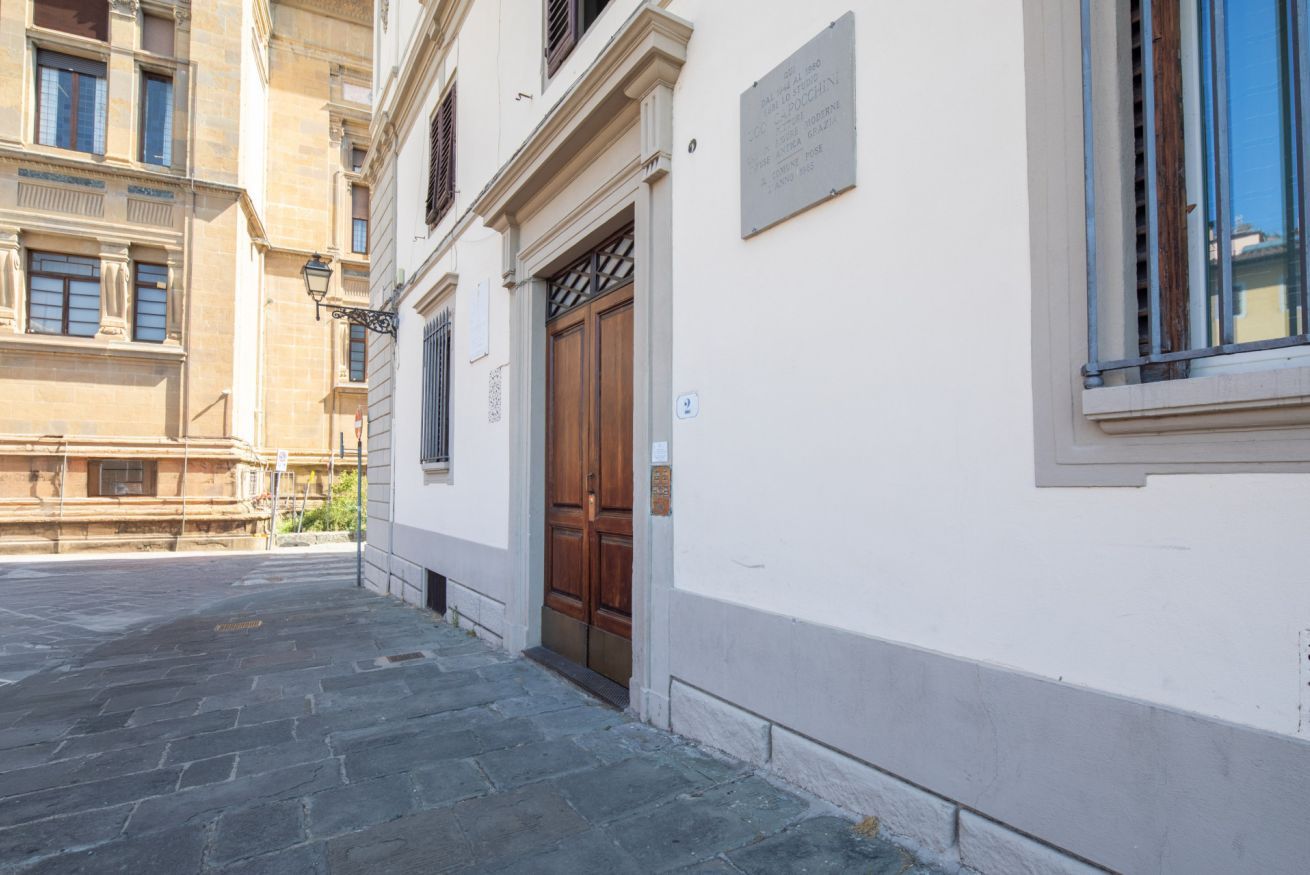 Una estrecha calle empedrada de piedra con un edificio que tiene una puerta de madera y una placa.