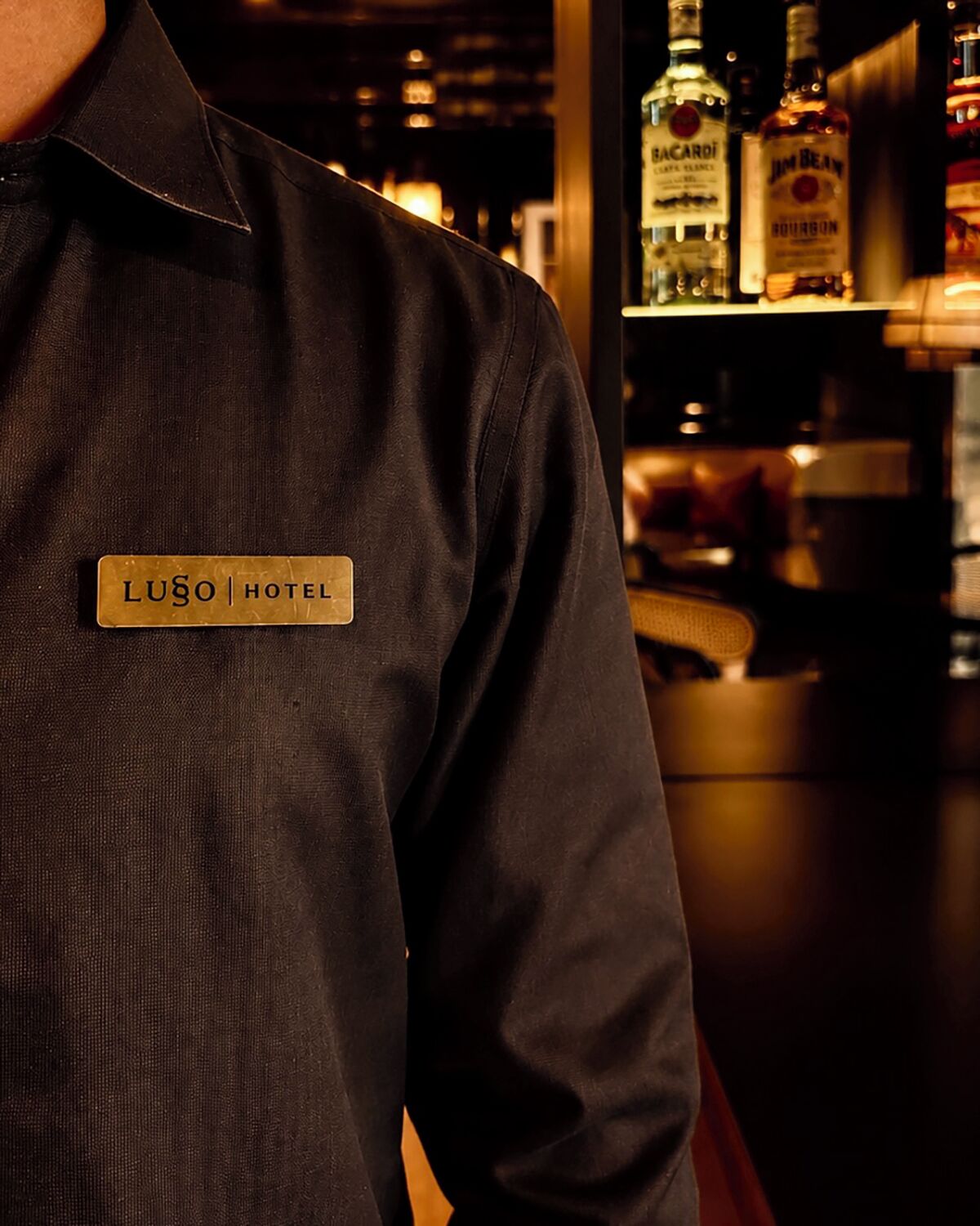 A person wearing a name tag with 'LUŠO HOTEL' visible.