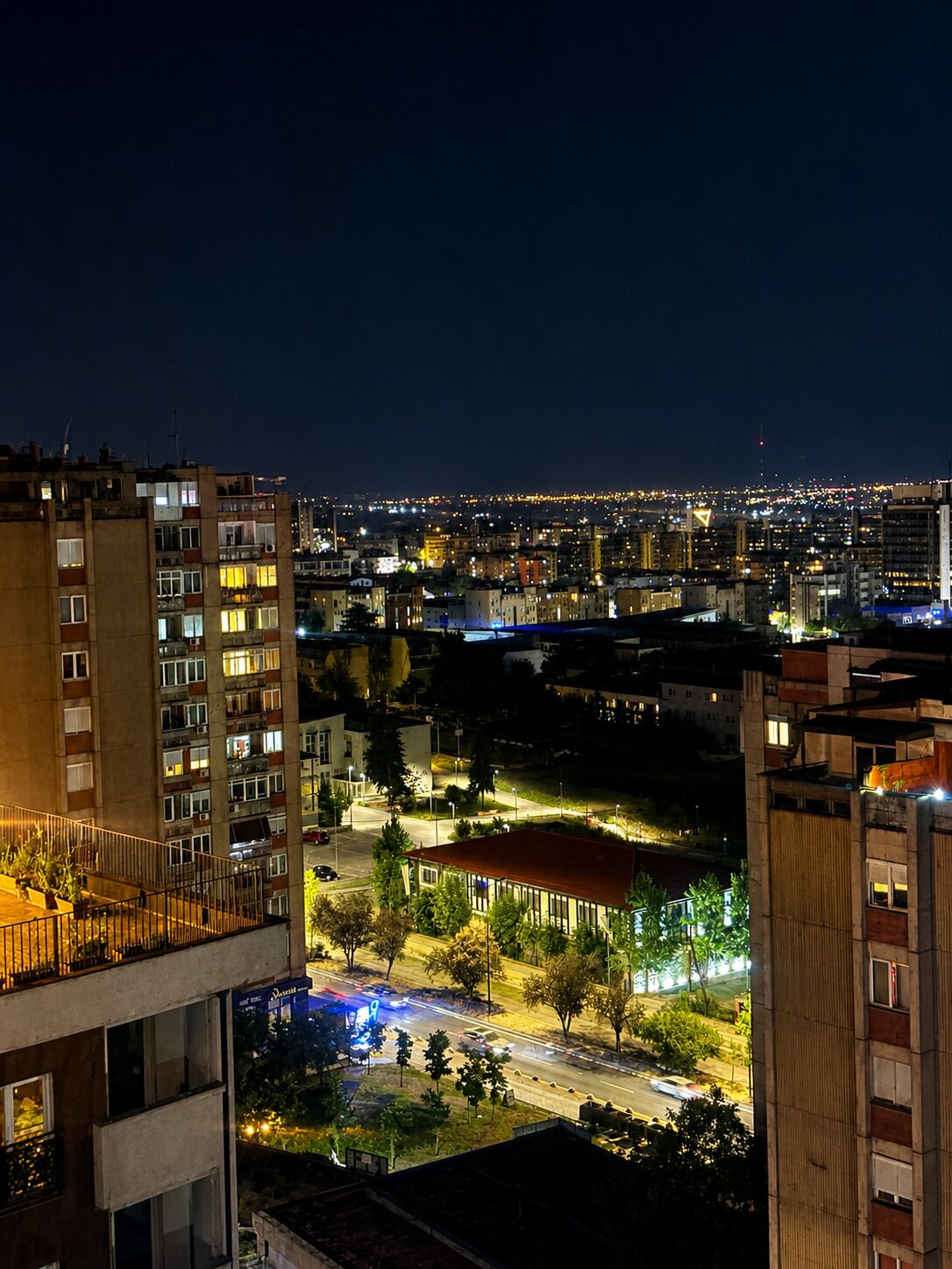 A nighttime cityscape with illuminated buildings and a well-lit street.
