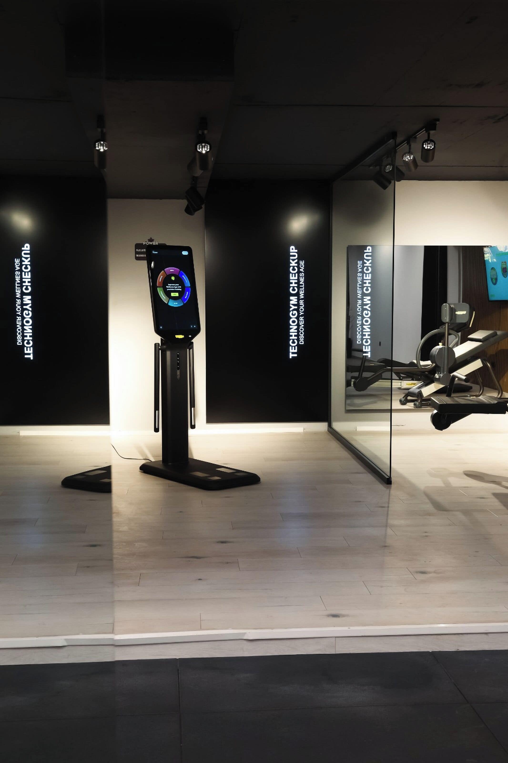 Um moderno centro de ginástica com um quiosque digital e equipamentos de exercício.