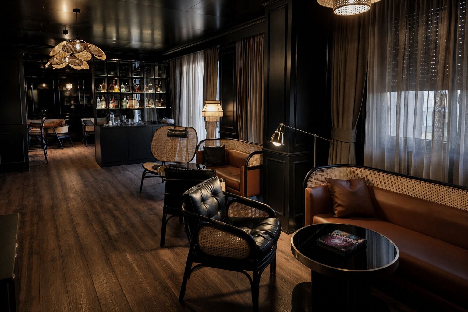 A dimly lit lounge area with leather sofas, a bar area with bottles, and a bookshelf.
