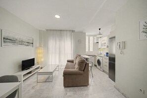 Un salon moderne avec un canapé, un téléviseur à écran plat et une table à manger.