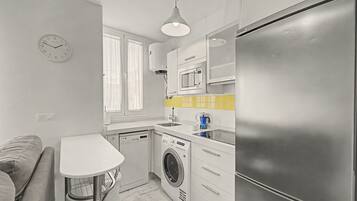 Une cuisine compacte équipée d’un lave-linge, d’un four à micro-ondes et d’un réfrigérateur.