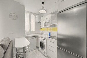 A compact kitchen with a washing machine, a microwave, and a refrigerator. - Goya 2ºB Apartment · In the Heart of Seville (Seville)