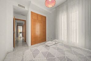 A bedroom with a large wardrobe, a bed with a patterned bedspread, and a view of a hallway. - Goya 2ºB Apartment · In the Heart of Seville (Seville)