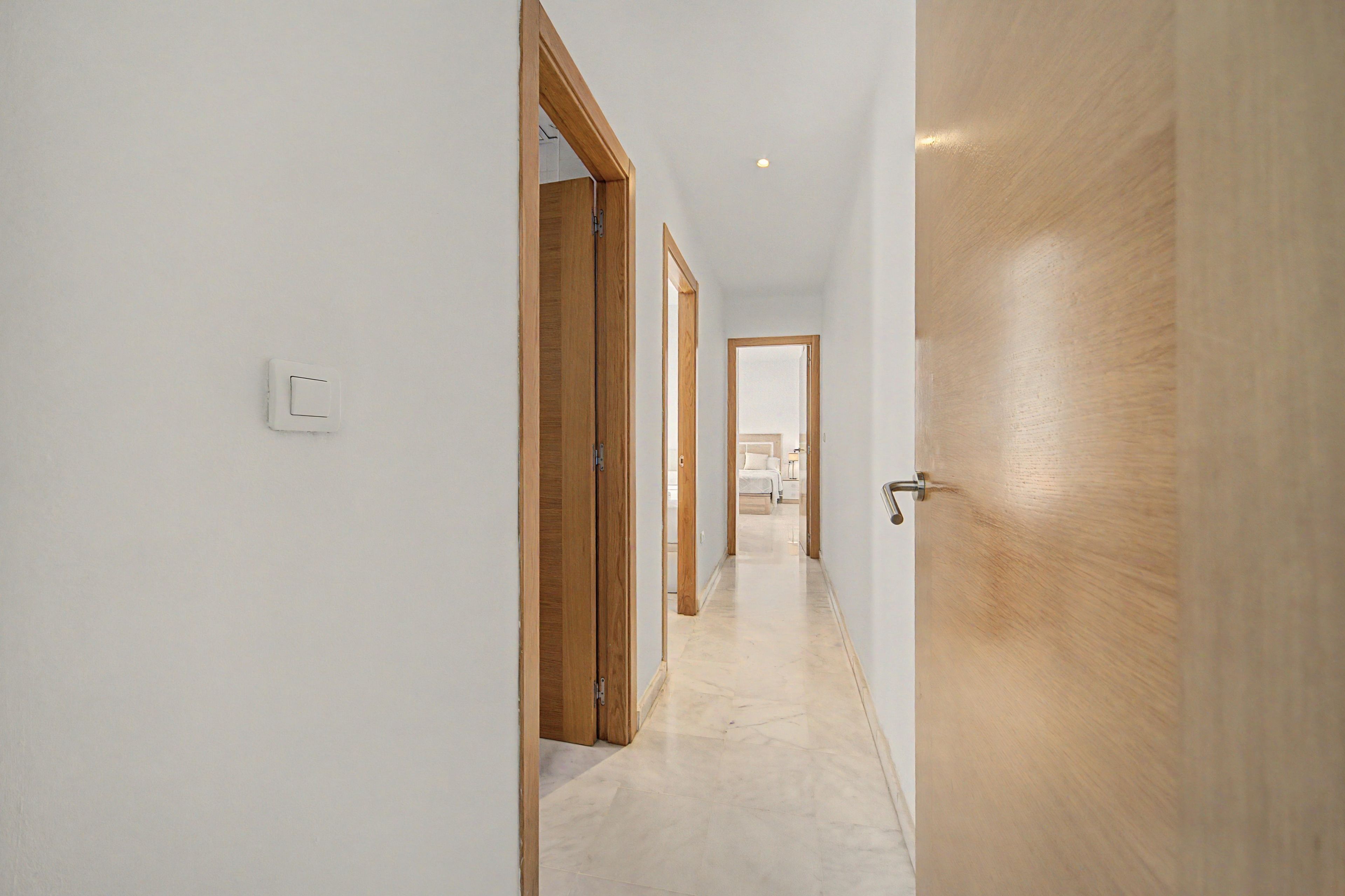 Un couloir avec des portes en bois et un interrupteur sur le mur.