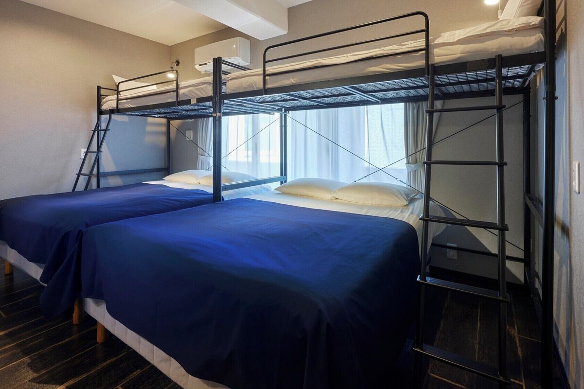 Habitación con literas, una escalera y una ventana con cortinas.