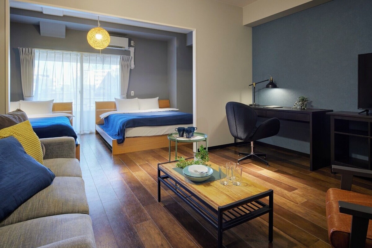 Una habitación de hotel moderna con sofá, dos camas, un escritorio y televisión.