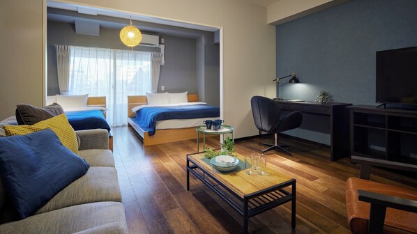 Una habitación de hotel moderna con sofá, dos camas, un escritorio y televisión.