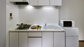 Cocina compacta con estufa, fregadero, microondas y un refrigerador pequeño.