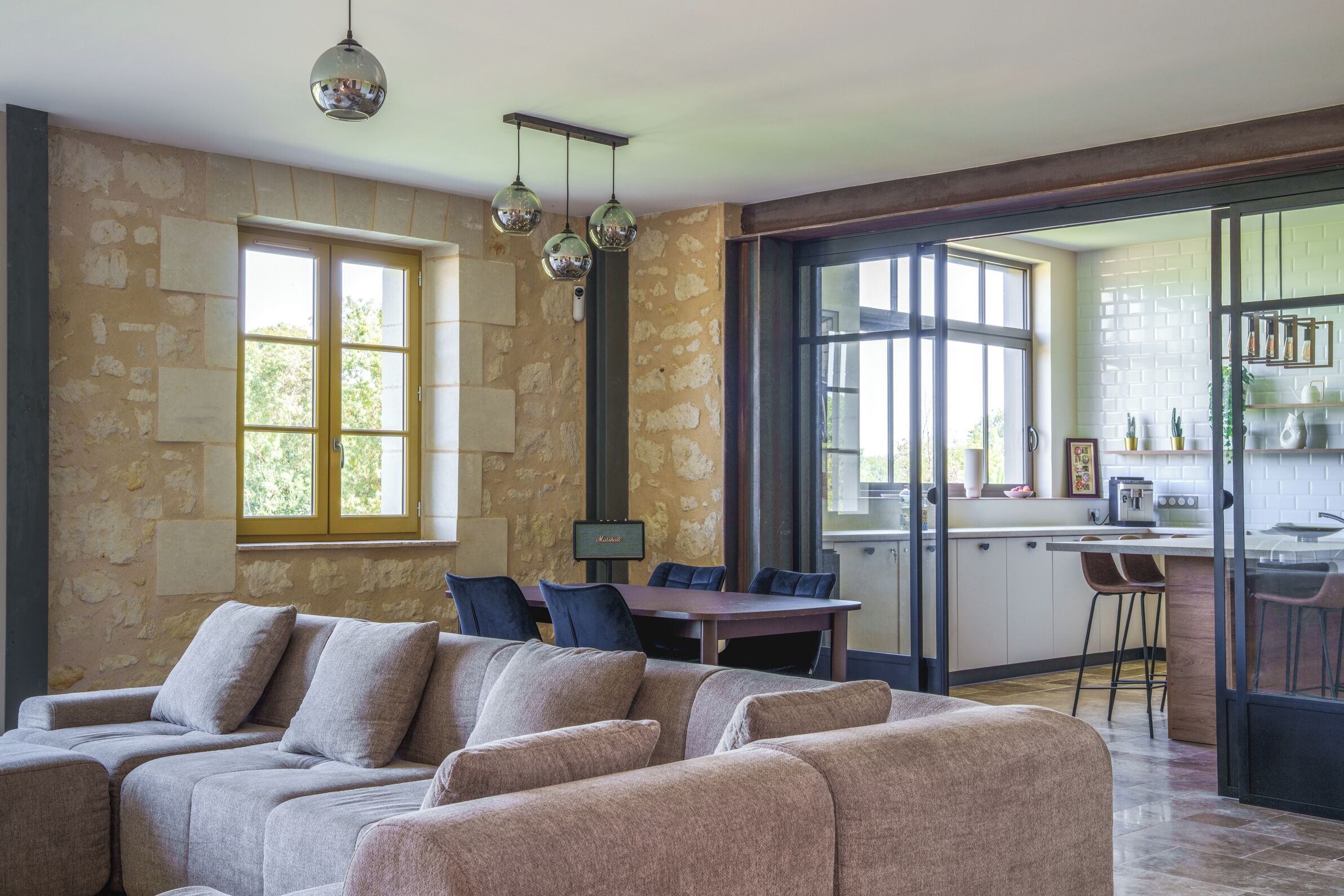 A modern living room with a stone wall, a sofa, and a dining area with a table and chairs.