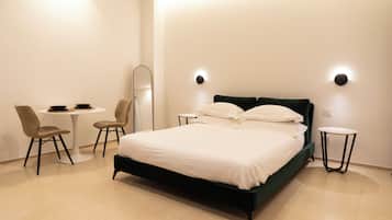 Une chambre à coucher moderne avec un lit, une chaise, une petite table et un miroir.