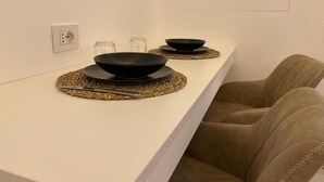 A white countertop with two black bowls on woven placemats, a glass, and a salt shaker. - Mas Collection - Dimora Zonno (Bari)