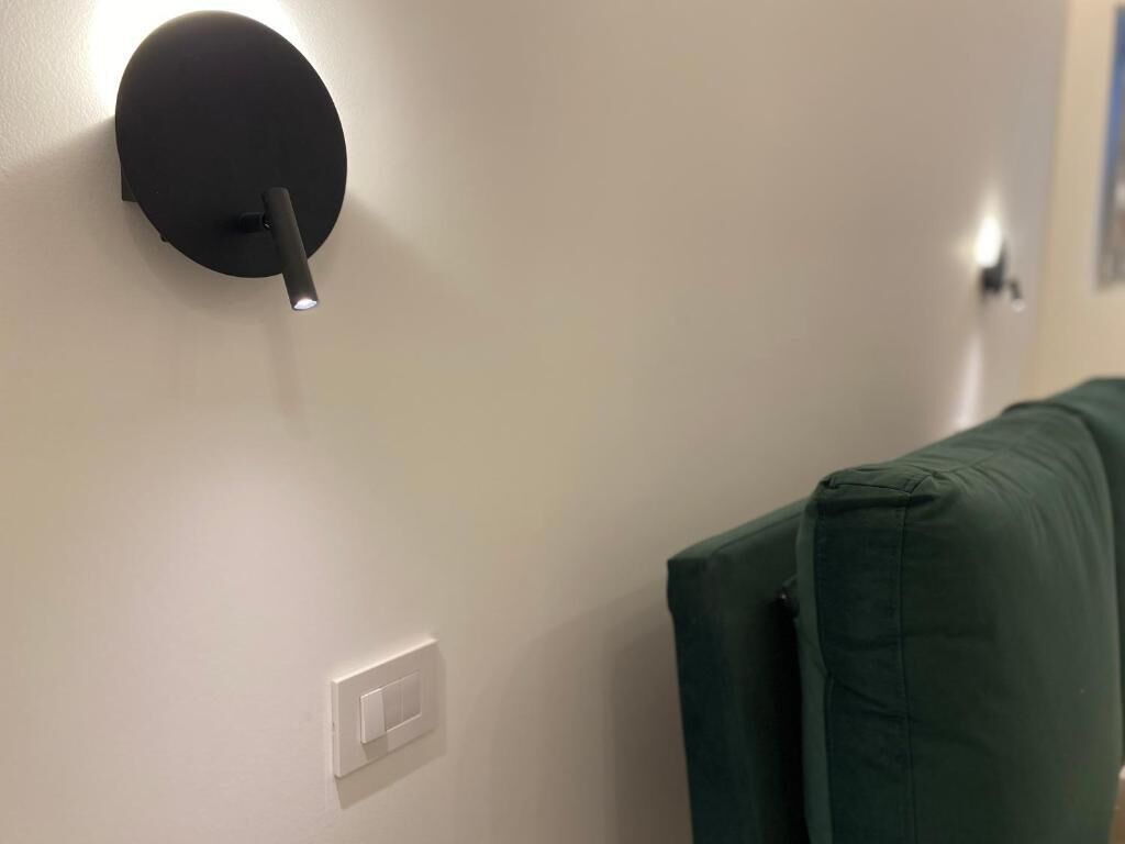 Un punto luce fissato al muro e un interruttore bianco su una parete liscia.