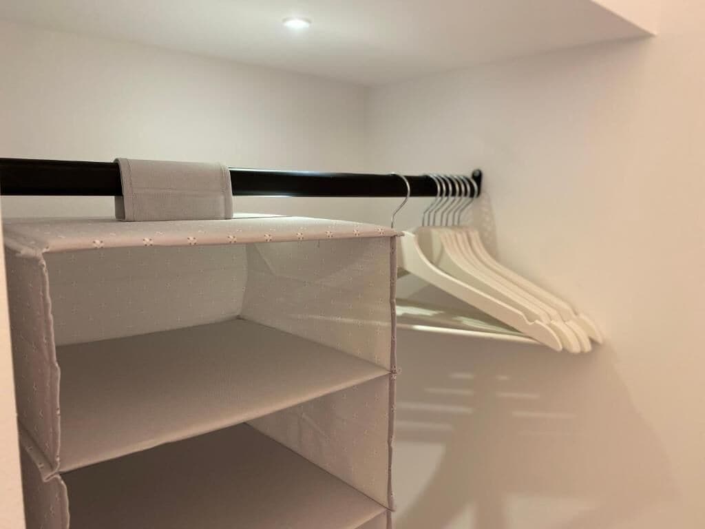 Een kamer met een stapelbed, een kledingroede en een witte muur.
