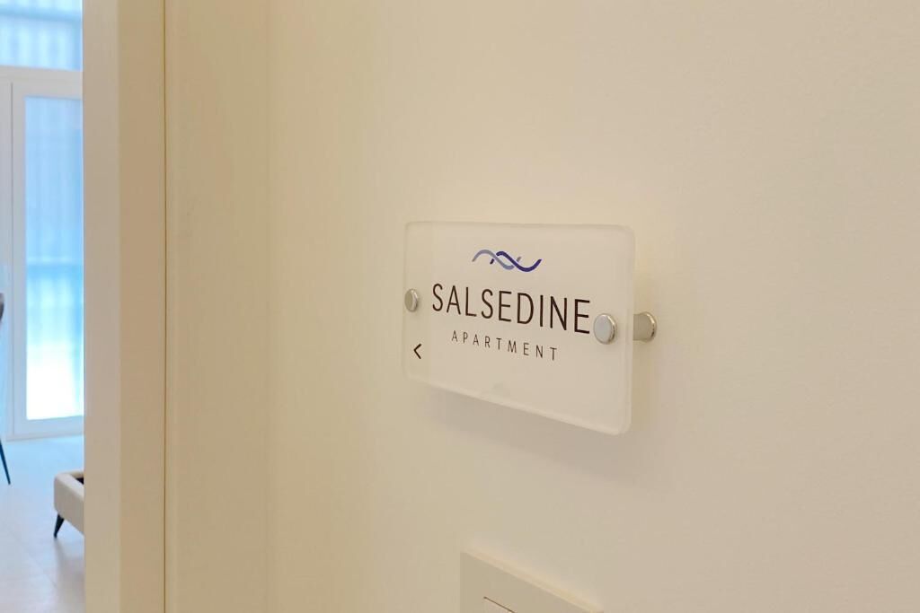 Een bord met de tekst 'SALSEDINE APARTMENT', voorzien van een pijltje dat naar links wijst.