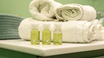 A bathroom with a white towel, a green towel, and three bottles of lotion on a white counter.