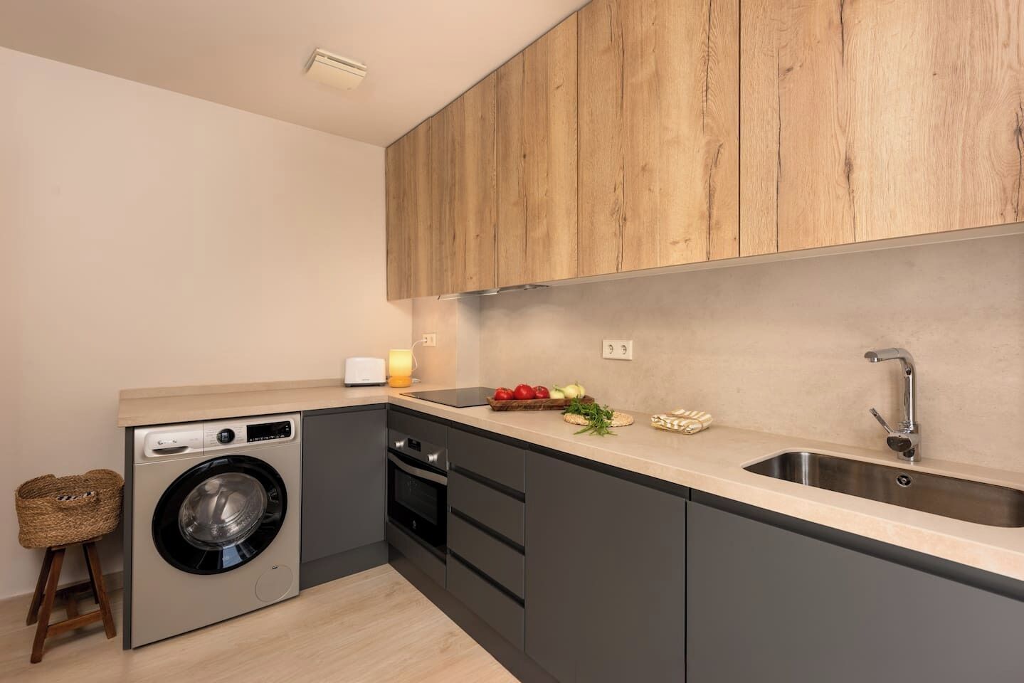 Eine kleine Küche mit Waschmaschine, Spüle und Holzschränken.