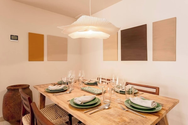 Ein Esszimmer mit einem Holztisch, gedeckt für sechs Personen, umgeben von Stühlen.
