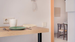 A room with a wooden table, a green plate, a white vase, a white telephone, and a wooden chair. - Estepona Old Town (200 meters from the beach) (Estepona)