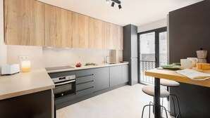 A modern kitchen with wooden cabinets, a built-in oven, a sink, and a dining area with stools. - Estepona Old Town (200 meters from the beach) (Estepona)
