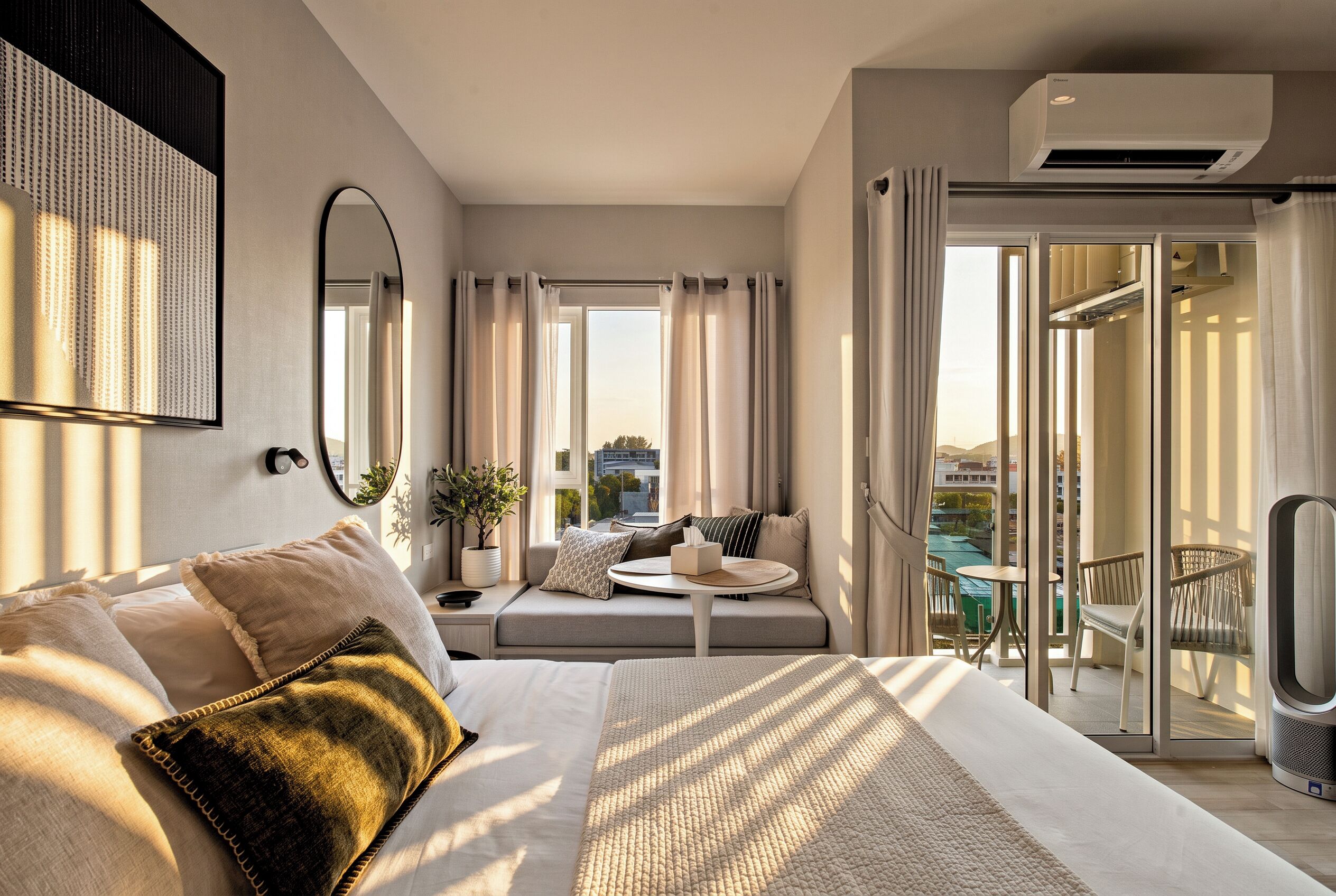 A modern bedroom with a large bed, a seating area with a view, and a balcony with a table and chairs.