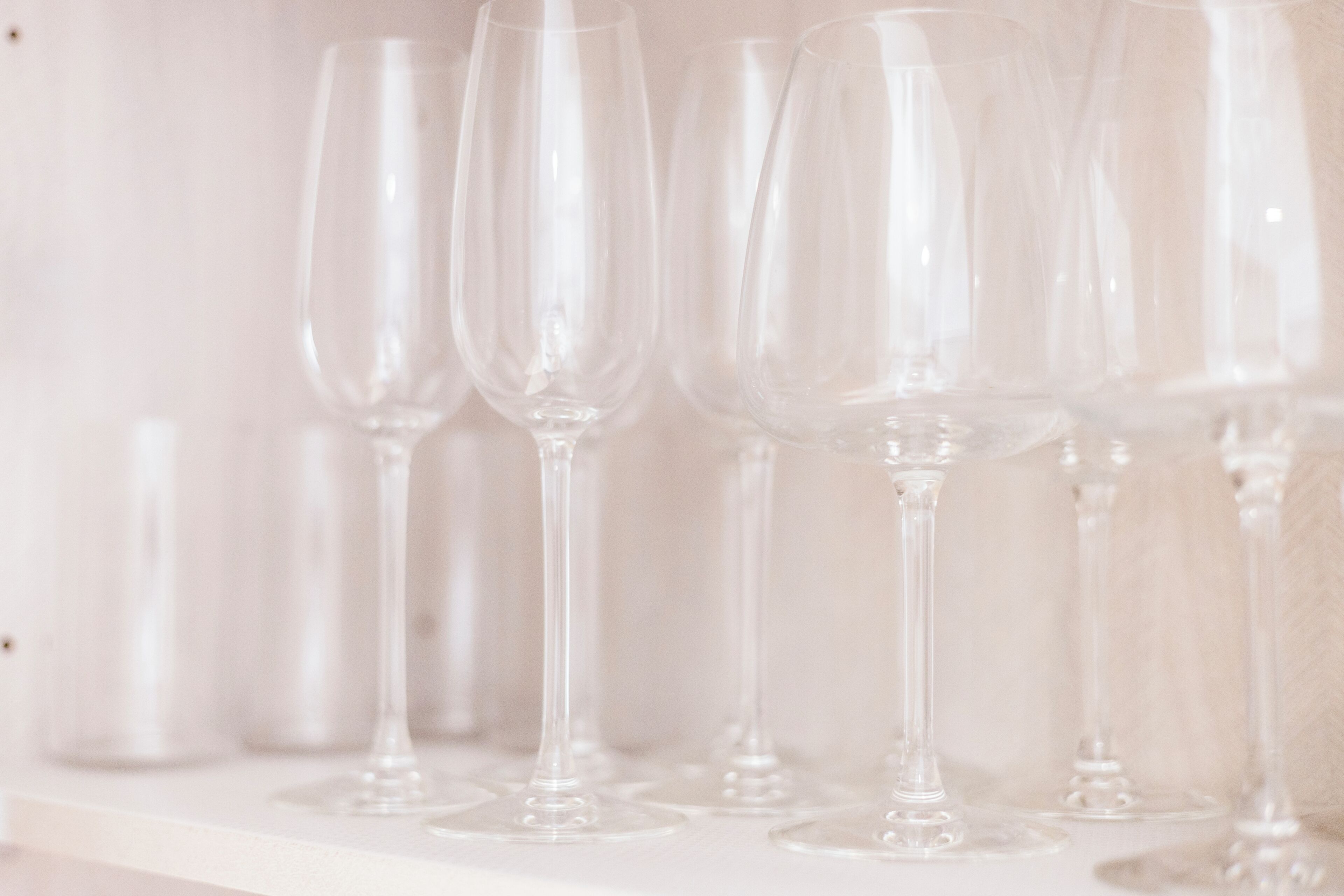 Varias copas de vino vacías sobre un estante blanco.