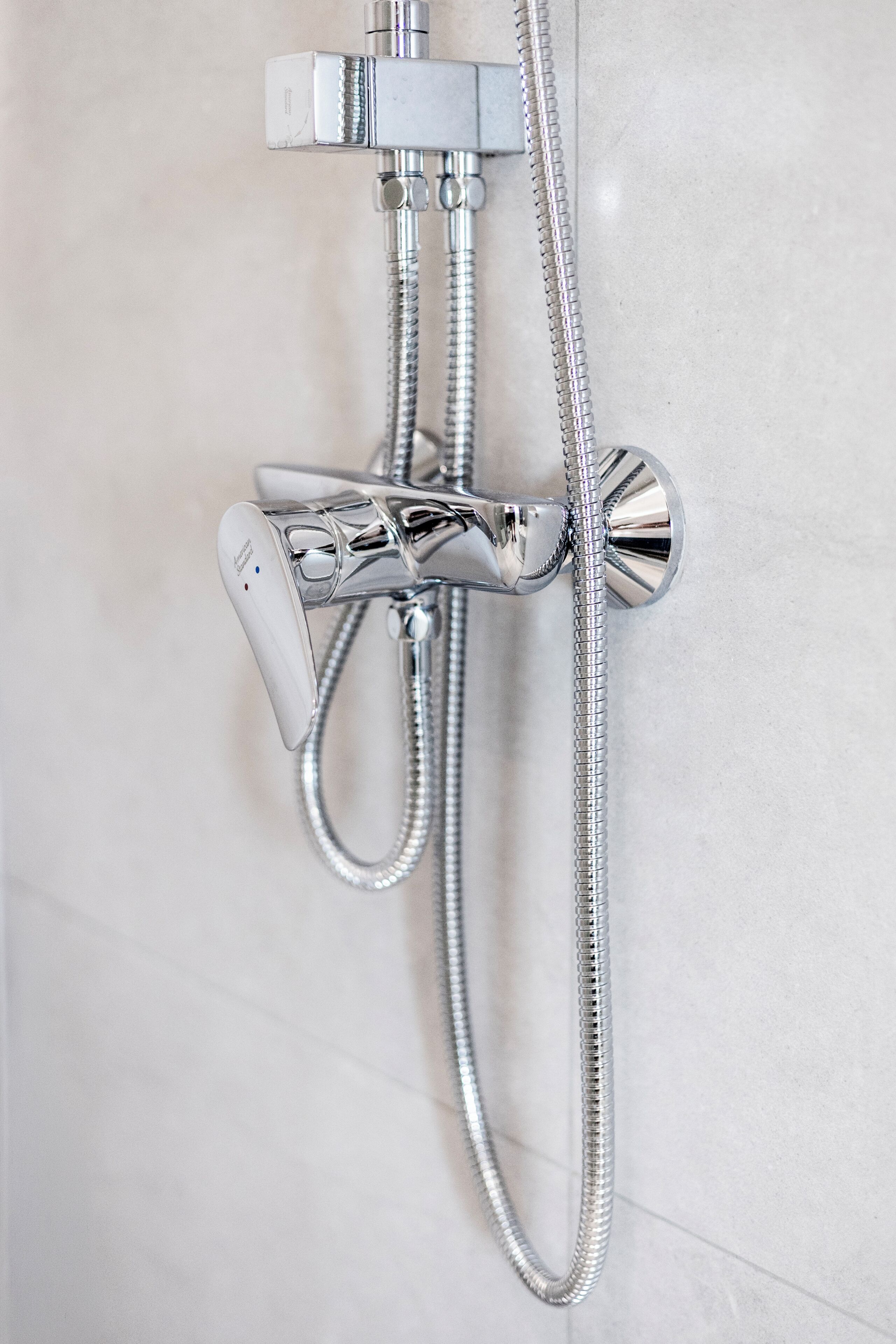 Un accesorio de ducha cromado con cabezal de ducha de mano y manguera flexible.