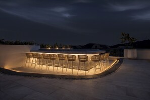 Eine Außenbar mit einer gebogenen Sitzgruppe und einem Pool.