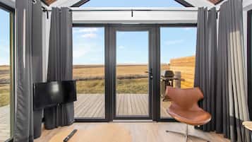Una habitación moderna con un amplio ventanal corredero que da a una terraza exterior.