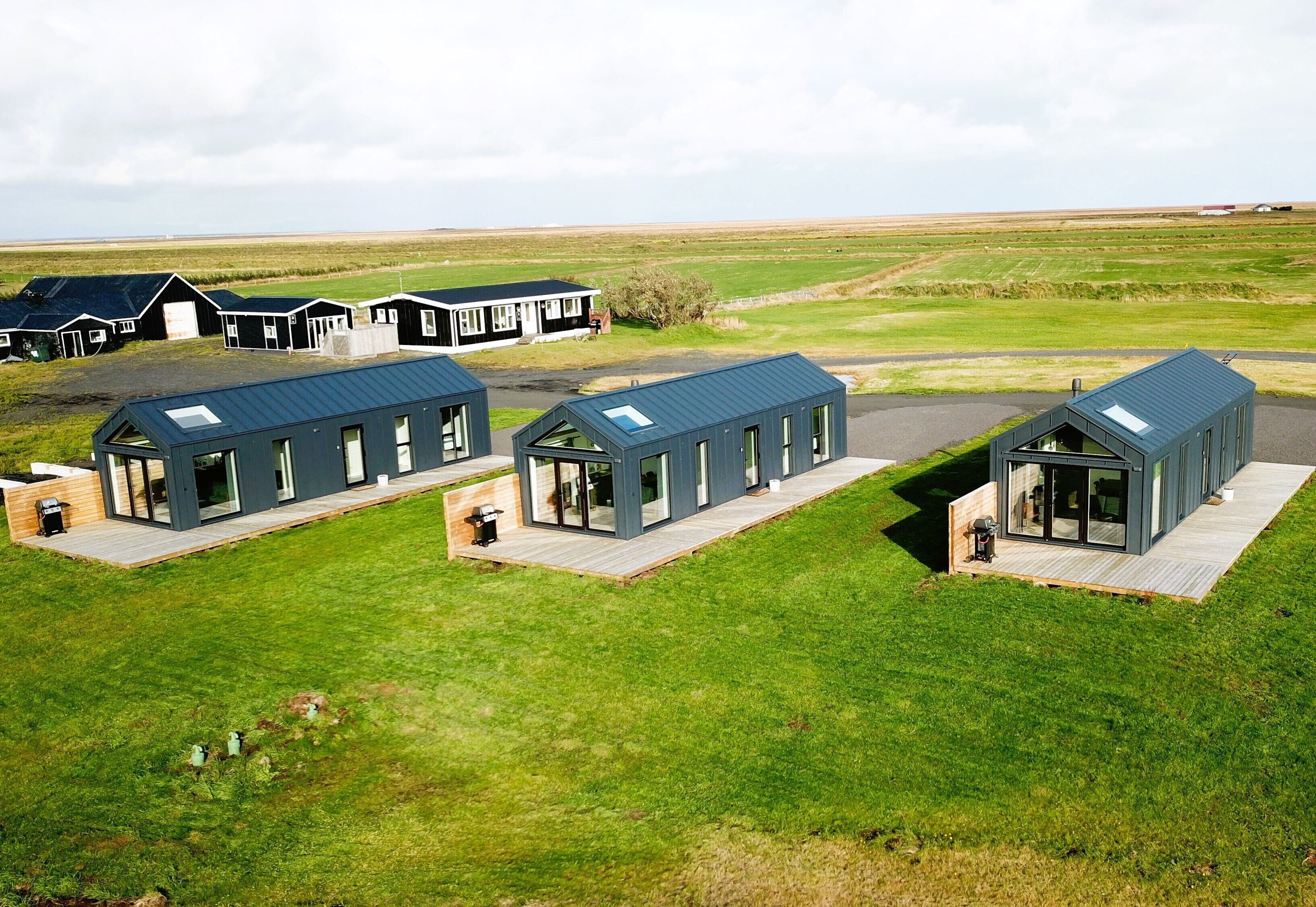 A modern building complex with multiple units, each featuring large windows and a flat roof.